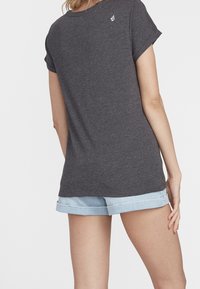 Grijze korte mouw t-shirt met een ronde hals en een klein logo op de achterkant, gecombineerd met opgerolde denim shorts. Gladde textuur.