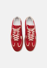 Baskets rouges en suède et textile, avec des lacets crème et un élément de design contrastant sur les côtés, dotées d'une semelle lisse.