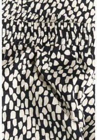 Tissu abstrait noir et blanc à motifs tachetés avec détail de taille élastique froncée.