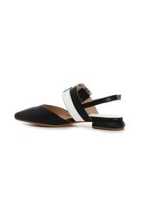 Zapato slingback de punta con parte superior de cuero negro, detalle de correa blanca y tacón bajo cuadrado. Textura suave con herrajes de correa ajustables.