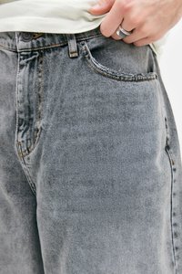 Grå denimjeans med et klassisk fem-lomme-design, der har synlige syninger, en knaplukning og en blød tekstur.