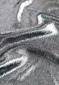 Tissu métallique argenté brillant avec des plis doux et une lumière réfléchissante créant une surface texturée et scintillante.