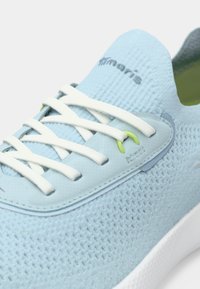 Ανοιχτό μπλε πλεκτό αθλητικό παπούτσι με άσπρα κορδόνια, λεπτομέρειες σε λαχανί γύρω από τις τρύπες, και άσπρη σόλα, που δείχνει το όνομα μάρκας Tamaris στην γλώσσα.