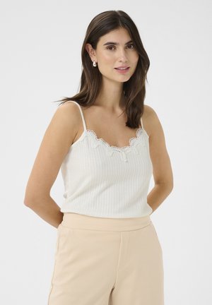 White ribbed tank top with lace trim at the neckline, featuring thin straps, paired with beige pants. The fabric has a soft, textured appearance.
