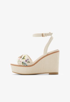 Sandales à plateforme blanches ornées de motifs floraux brodés à l'avant, avec une bride de cheville assortie et un talon compensé texturé.