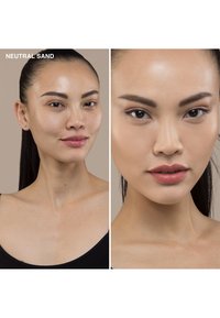Makeupprøver i "Neutral Sand" på en models hud, som viser en jevn, glatt tekstur og naturlig finish. Modellen har på seg en svart topp.
