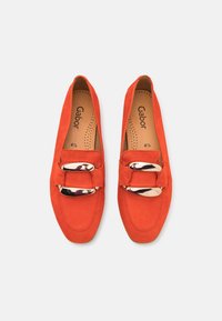 Světlé oranžové semišové slip-on mokasíny s velkými lesklými zlatými sponami, značené stélky a velikostí 4½ uvnitř.