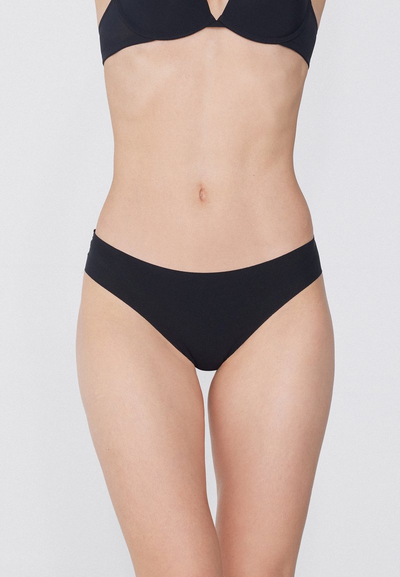 Černé bikiny s hladkým povrchem, nízkým pasem a jednoduchým, minimalistickým střihem. Žádné vzory ani viditelné kovové detaily.