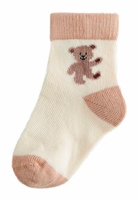Lyse creme sokker med en pink ribbet manchet, der har et brunt bjørne-design på siden samt en pink hæl og tå. Blød strikket tekstur.