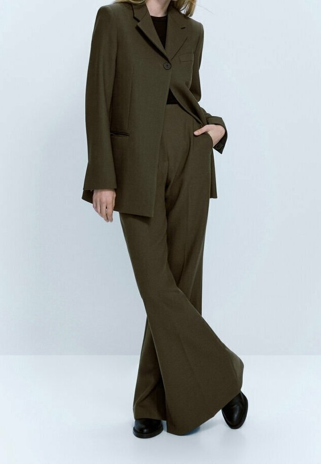 Costume ajusté vert olive avec une veste à un bouton, dotée d'une poche avant et d'un pantalon large. Tissu lisse avec une texture subtile.