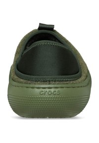 Scarpa slip-on verde oliva con un'esterno morbido e testurizzato, pannello in tessuto elastico e suola in gomma con un pattern a punti. Logo su un lato.