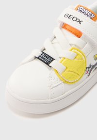 Λευκό δερμάτινο αθλητικό παπούτσι με υφασμένο κίτρινο τενιστικό μπαλάκι από τσόχα, ελαστικές κορδόνια και λογότυπο Looney Tunes στο λουράκι και στην πλευρά.