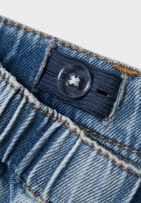 Pás s gumičkami z denimu, so stredným čírym plastovým gombíkom a kontrastným béžovým prešívaním.