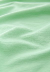 Hele roheline puuvillane kangas pehme tekstuuriga, millel on peened kortsud ja sile viimistlus.