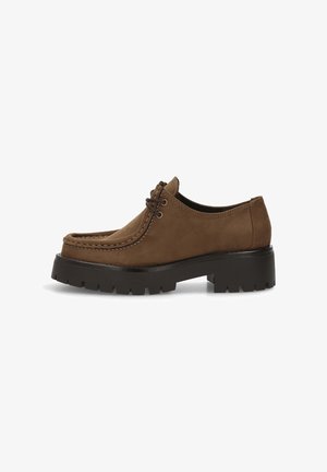Zapato de ante marrón con punta redondeada, costuras en contraste, parte delantera con cordones y una suela de goma negra gruesa con surcos dentados.