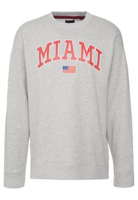 Sweatshirt gris à col rond avec "MIAMI" en lettres rouges en arc, centré au-dessus d'un petit graphique de drapeau américain. Texture douce, design décontracté.