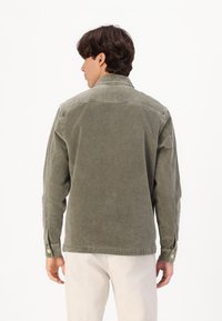 Olivengroene katoenen jacket met een kraag met knoopsluiting, lange mouwen en manchet. Zachte textuur, rechte snit en minimale stikseldetails.