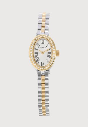 Montre bracelet ovale Timex avec bracelet en métal doré et argenté, lunette dorée avec des cristaux, cadran blanc et chiffres romains noirs pour les heures.