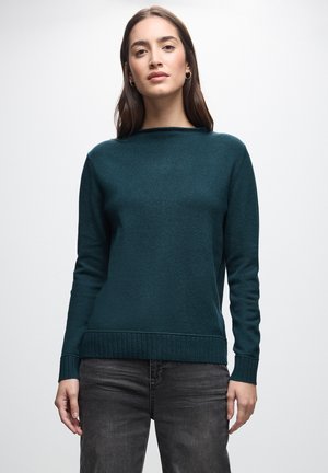 Teal striktrøje med bred rund hals, ribbet kant og lange ærmer, der har en blød tekstur og medium vægt. Kombineret med mørke jeans.