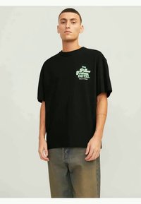 Black cotton oversized T-shirt featuring green text: "The Pillow Fortress HOTEL" with "CALL IT A NIGHT" below. Short sleeves and round neck.