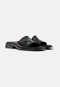 Black slide sandals with a low block heel, features colorful geometric embroidery on the upper and a smooth, matte finish.