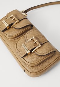 Brown leather handbag with two front pockets, gold hardware accents, and a textured surface. Features a single adjustable strap.