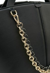Borsa a tracolla in pelle nera con catenella nera e dorata. Presenta un moschettone dorato e una superficie testurizzata per un dettaglio aggiuntivo.