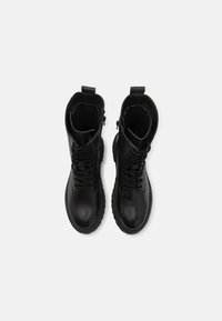 Černé kožené kotníkové boty s šněrováním vpředu, bočními zipy a texturovanou podrážkou. Jednoduchý design s hladkým povrchem a poutky na stažení.