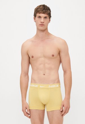 Gelbe Baumwollboxershorts mit einem weißen elastischen Bund, der das Nike-Logo trägt. Das Design umfasst eine Fronttasche und einen taillierten Schnitt.