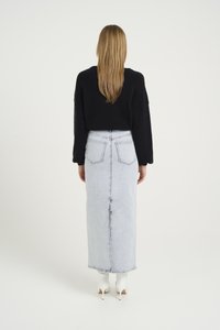 Svart strikket kort genser paret med en lyseblå denim maxi skjørt, som har baklommer og høy livhøyde. Hvite hæler fullfører looken.