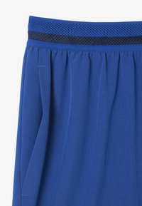 Pantaloni sportivi blu con vita elastica in tessuto testurizzato blu scuro, tasche laterali e un tessuto liscio con una leggera lucentezza.
