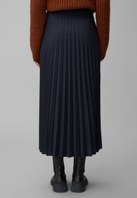 Dark navy pleated skirt with a fitted waistband, made from smooth fabric, paired with knee-high black boots. Visible vertical pleats.