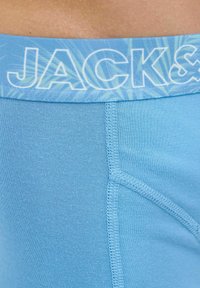 Light blue boxer shorts with a soft, smooth texture; feature a patterned waistband with "JACK&" in bold white letters.