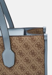 Bolso tote de diseño marrón con estampado y acentos de cuero azul claro, que presenta un diseño estructurado y asas dobles para llevar.