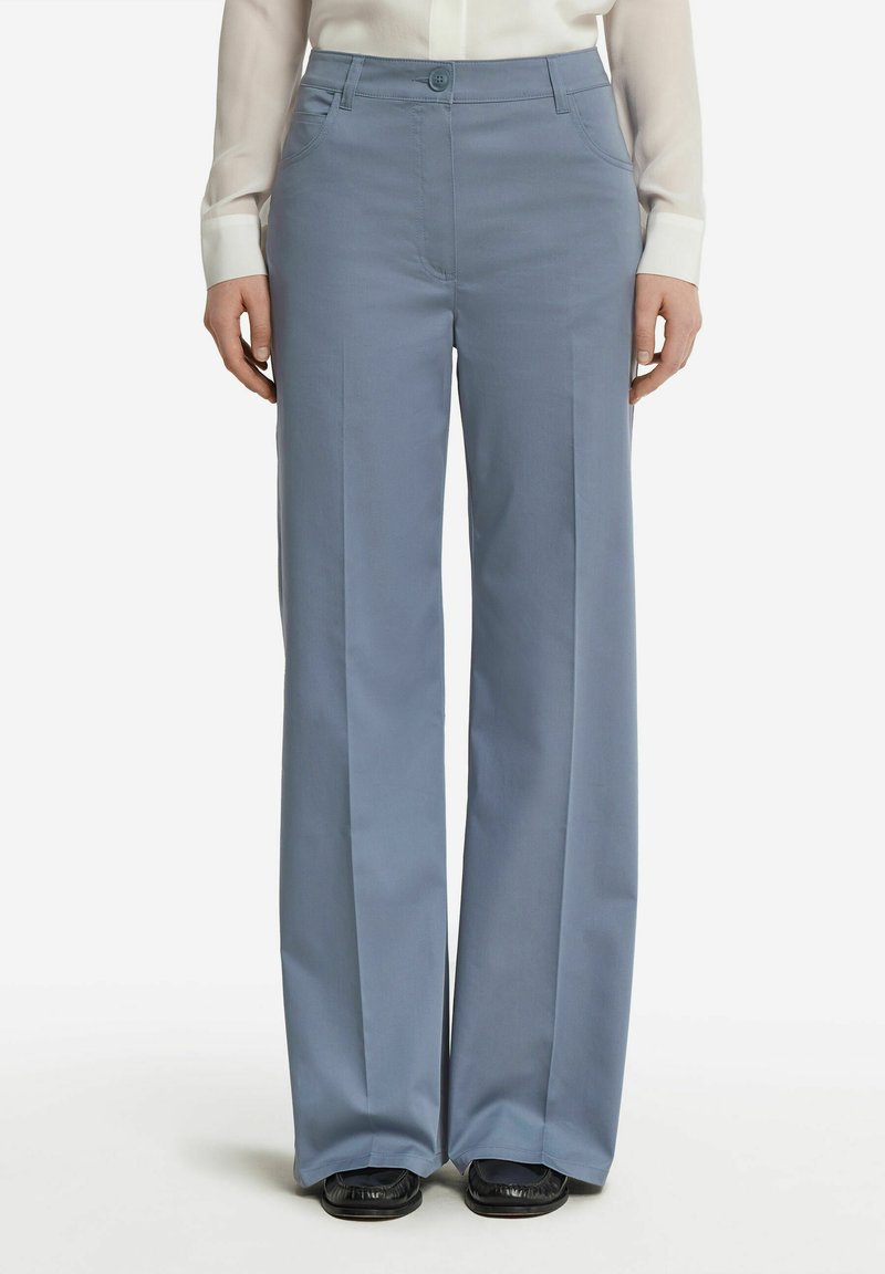 Ljusblå vida byxor gjorda av mjukt tyg, med knäppning, framfickor och en skräddarsydd silhuett.