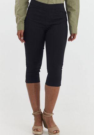 Schwarze Capri-Hosen mit einer glatten, dehnbaren Textur und einem figurbetonten Design. Sie verfügen über einen hohen Bund und Reißverschlüsse an den Knöcheln für stilistische Anpassungen.
