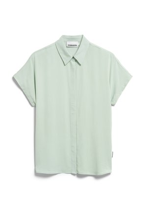 Blouse à manches courtes avec col, de couleur vert menthe clair. Fabriquée en tissu lisse avec patte de boutonnage à l'avant. Légère brillance, design minimaliste.