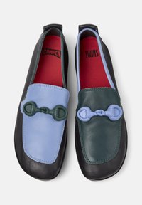 Bunte Slipper mit einem hellblauen und dunkelgrünen Lederdesign, versehen mit einem dekorativen kettenähnlichen Element an jedem Schuh.