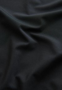 Schwarzer Stoff mit glatter, leicht glänzender Textur, der weiche Falten und Knicke zeigt. Die Oberfläche ist gleichmäßig ohne erkennbare Muster oder Akzente.