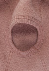 Ljust rosa filtprodukt med en rund öppning kantad med ribbad trim. Mjuk textur med synlig sömnad och lager-på-lager-utseende.