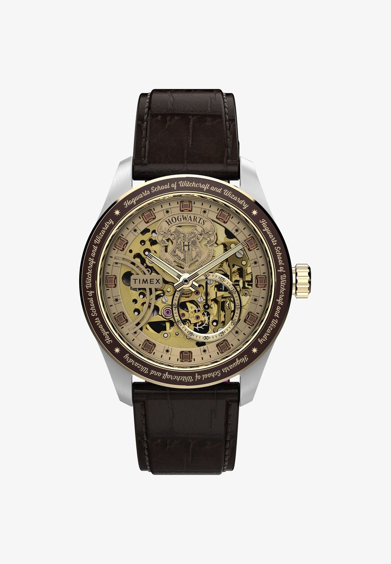 Αναλογικό ρολόι χειρός Timex με το έμβλημα του Χόγκουαρτς, διαφανείς χρυσούς μηχανισμούς, καφέ δερμάτινο λουράκι και κείμενο "Hogwarts School of Witchcraft and Wizardry".