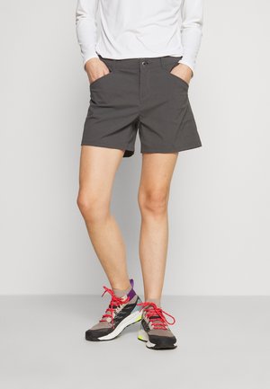 Grijze shorts met een rechte snit, voorzien van twee zijzakken en een knoopsluiting, gecombineerd met grijze en zwarte sportschoenen met rode veters.