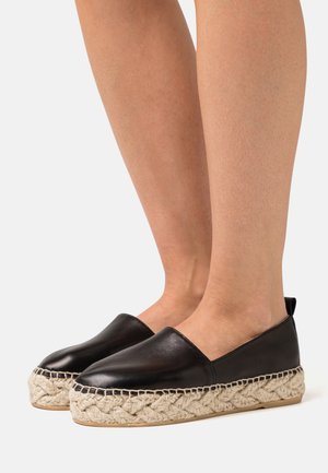 Espadrilles en cuir noir avec une plateforme en jute tissé et une semelle en caoutchouc. Présentent un bout lisse et arrondi ainsi qu'un design à enfiler.