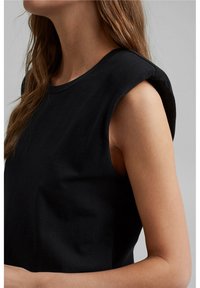 Top senza maniche in cotone nero con scollatura rotonda e cuciture sulle spalle arrotondate, caratterizzato da una consistenza liscia e una silhouette aderente.