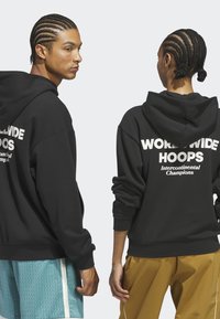 Two people with braided hair wearing black hoodies with "WORLDWIDE HOOPS Intercontinental Champions" printed on the back.