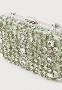 Zelená saténová kabelka s komplexními krystalovými ozdobami a stříbrným zapínáním. Kulatý tvar s různými velikostmi a vzory drahých kamenů.