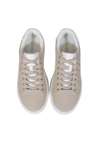 Sneakers beige con tomaia in suede morbido e accenti bianchi. Presentano occhielli dorati, lacci piatti e un pannello laterale testurizzato. Suola in gomma.