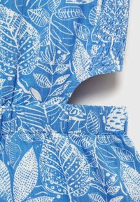 Modra tkanina z belimi motivi listov; vsebuje zbrane dele, teksturirano smockanje in okrogel ovratnik.