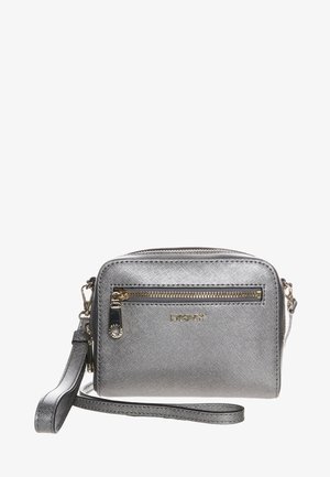 Petit porte-poignet argenté métallisé DKNY avec poche zippée à l'avant, fermeture éclair dorée et sangle de poignet amovible sur fond blanc.