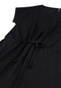 Zwarte katoenen jurk met korte mouwen, een relaxte pasvorm, elastische tailleband en een strikaccent met trekkoord. Soepele textuur, eenvoudig ontwerp.